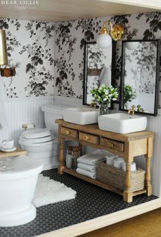 a doll house bathroom with sink, toilet and vanity in the corner is decorated with black and white floral wallpaper