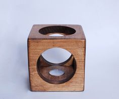 a wooden object with two holes in the middle and one hole on the side, sitting on a white surface