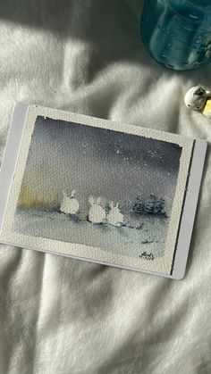 a watercolor painting of three birds on a white sheet next to a blue bottle