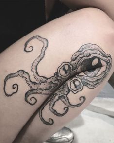 an octopus tattoo on the leg of a woman's thigh, with her eyes open