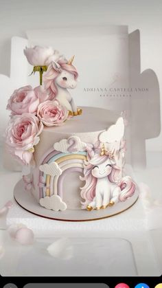 there is a cake decorated with pink roses and an unicorn on it's side