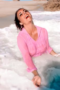 a woman is laying in the water at the beach with her eyes closed and mouth wide open