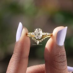 a woman's hand holding an engagement ring with two stones on the top and bottom