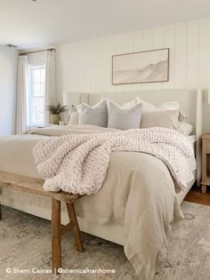 a bedroom with a large bed covered in white blankets and throw pillows on top of it