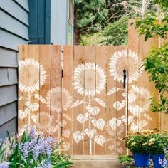 a wooden fence with sunflowers painted on it and potted plants next to it