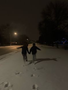 two people walking in the snow at night