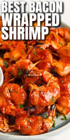 the best bacon wrapped shrimp is served on a plate with dipping sauce and parsley