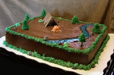 a cake that is shaped to look like a river with trees on the side and a house in the middle