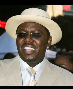 a man in a suit and tie wearing a white hat with sunglasses on his face