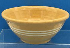 a yellow bowl sitting on top of a glass shelf next to a blue wall and floor