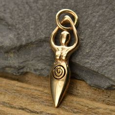 a gold pendant with a spiral design hanging from it's side on a piece of wood