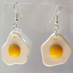 two fried eggs are hanging from silver earwires