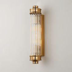 a wall light that is on the side of a white wall with gold trimmings