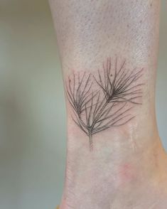 a small pine tree branch tattoo on the ankle