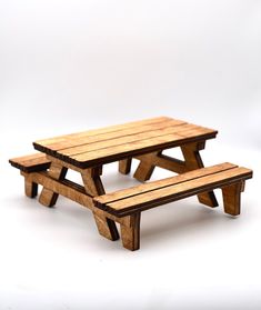 two wooden benches sitting next to each other on top of a white surface with no one around them