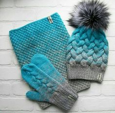 two knitted hats and mittens on top of each other next to a brick wall