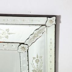 an old mirror with flowers painted on the side and black trim around the edges, hanging on a wall