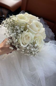 a bride's bouquet with white roses and baby's breath is on her wedding day