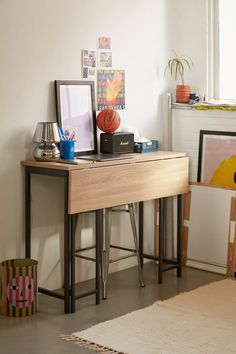 a wooden desk topped with a basketball on top of a hard wood floor next to a window