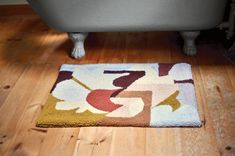 a bath tub sitting on top of a wooden floor next to a rug covered in flowers