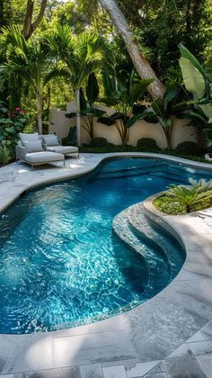 an outdoor swimming pool surrounded by greenery and trees with lounge chairs on the side