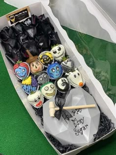 a box filled with halloween cupcakes on top of a green table