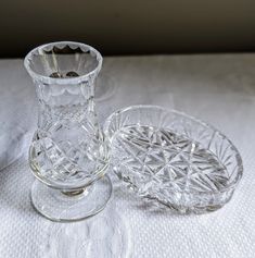 two clear glass vases sitting on top of a white tablecloth covered table cloth