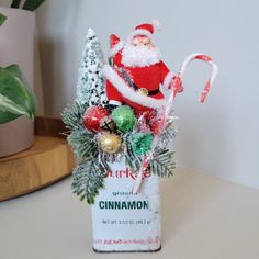 a christmas decoration with candy canes and santa clause in it on a table next to a potted plant