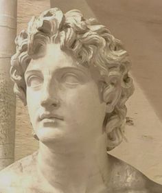 a statue of a man with curly hair and eyes closed in front of a column