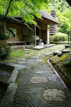 a stone path leading to a small building in the woods with trees and rocks on either side