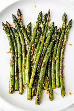 cooked asparagus on a white plate topped with seasoning and sprinkles