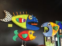 two colorful fish hanging on the wall next to a clock and other items in front of it