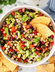 a white bowl filled with mexican salad and tortilla chips