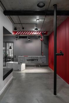 an empty room with red walls and black metal pipes on the floor, along with a sign that reads logity