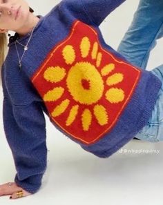 a young woman is posing with her hand on her hip while wearing a blue sweater and jeans