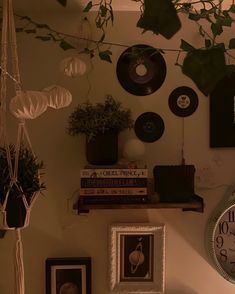 there is a clock on the wall next to pictures and plants