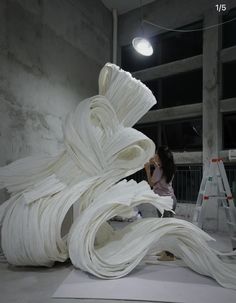 a woman is working on a sculpture in the middle of a room with concrete walls