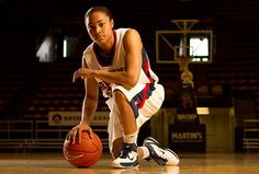 a female basketball player crouching down with a ball in her hand