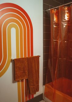 an orange shower curtain in a bathroom next to a wall with a rainbow design on it