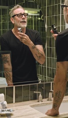 a man is looking at his reflection in the mirror