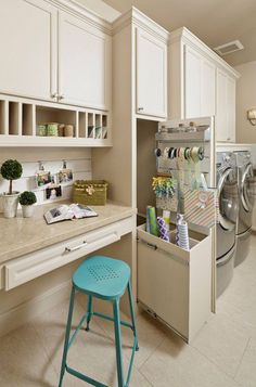 a washer and dryer in a small room with white cabinets, counter tops and drawers