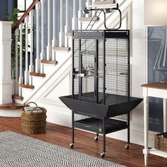 a black birdcage sitting on top of a wooden floor next to a stair case