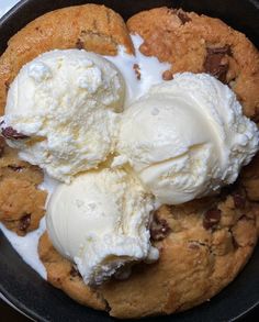 two scoops of ice cream are in a skillet with chocolate chip cookies on the side