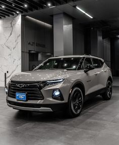 a silver chevrolet suv is parked in a large room with black and white marble walls