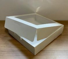 an empty white box sitting on top of a wooden table