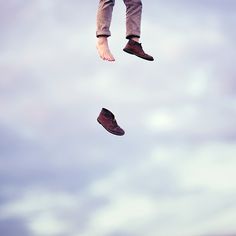 a person jumping high into the air with their shoes off and feet in the air