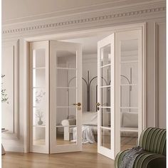 an open door leading to a bedroom with white walls and wood floors, along with a green chair