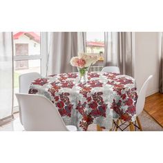 a dining room table covered with a red flowered tablecloth next to a window