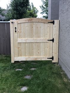 a wooden gate in the grass next to a building