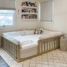 a baby's crib in the corner of a room with two windows and a rug on the floor